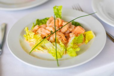 Seramik tabakta soyulmuş karides eti.