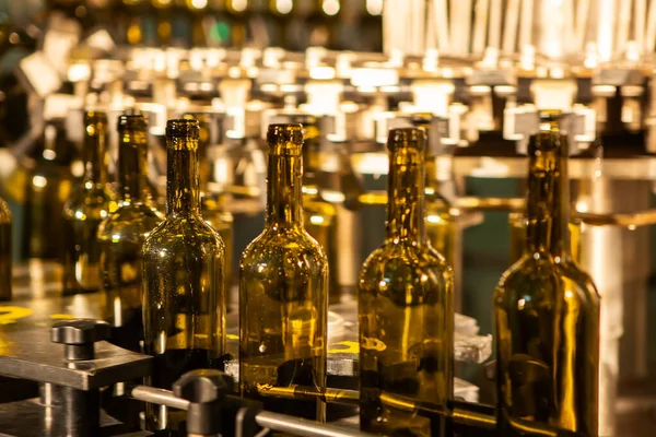 Garrafas de vidro não rotuladas em máquina de engarrafamento na vinícola moderna — Fotografia de Stock