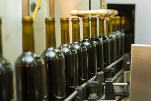 Unlabeled glass bottles in bottling machine at modern winery — Stock Photo, Image