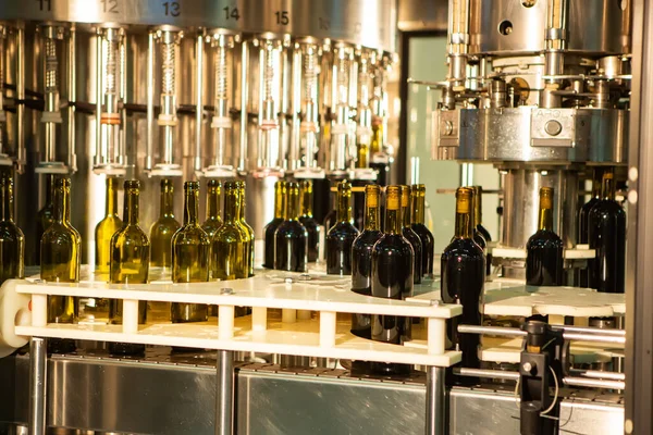 Unetikettierte Glasflaschen in Abfüllanlage in modernem Weingut Stockbild