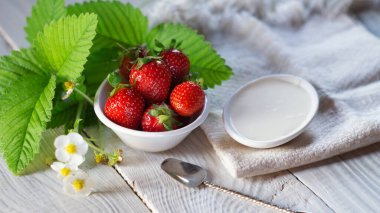 Yakınlarda ekşi kremalı ve çiçekli taze çilekler.