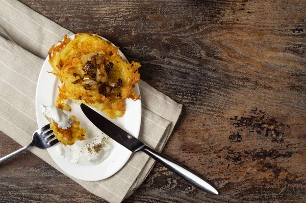 Panqueques de patata con cebolla frita y crema agria servidos en mesa de madera — Foto de Stock