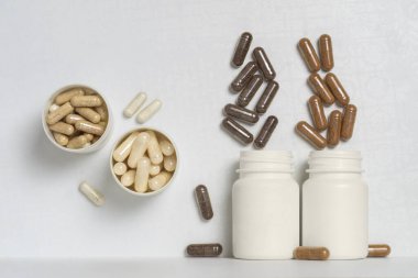 Dikey düzlemlerde beyaz plastik kavanozlarda beslenme takviyeleri ya da vitaminler içeren kapsüller