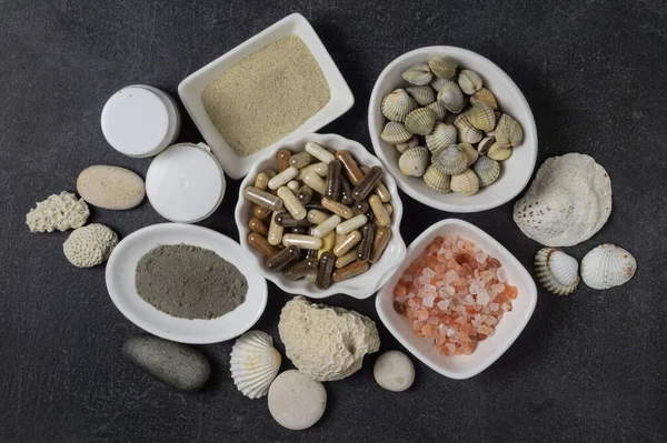 Kapsüllerde beslenme takviyeleri, tabaklarda pembe tuz kristalleri ve deniz mineralleri.