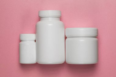 Pembe arka planda üç boş plastik kavanoz.