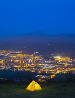 camping tent at night with the lights of the city in the background, Irun in Euskadi clipart