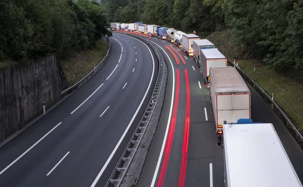 stack of trucks in a long traffic jam on the freeway at night