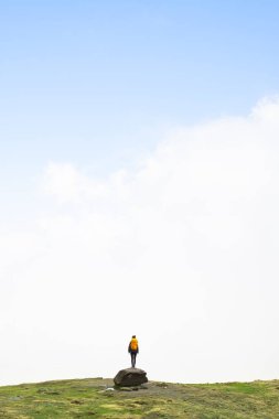Girl on a rock looking for the way forward in fog in the Pyrenees National Park, France. Concept of looking for solutions