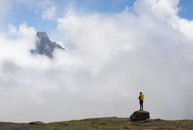 Girl with orange backpack looking at the Midi dOssau mountain in the Pyrenees National Park, France.