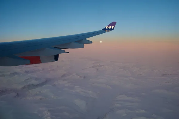 KOPENHAGEN, DÄNEMARK - 24. NOV 2018: Blick aus der Flugzeugkabine auf die Tragfläche bei Sonnenuntergang über den Eisbergen Grönlands — Stockfoto