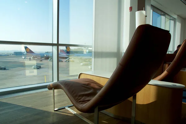 FRANKFURT, ALLEMAGNE - 11 NOV 2017 : Chaise longue confortable tapissée de cuir marron clair dans le salon des grands voyageurs de l'aéroport avec vue sur l'avion sur l'aire de trafic — Photo