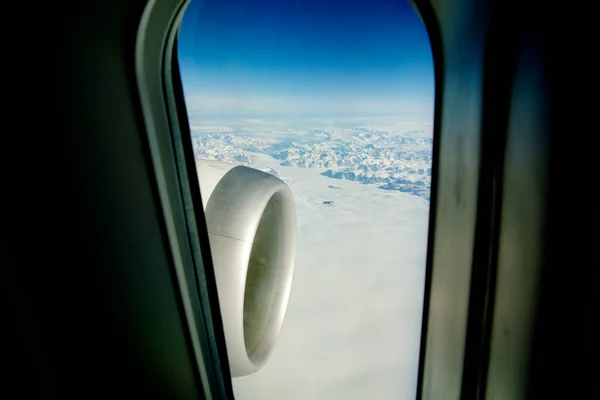 GREENLAND - 10 May 2018:ジェットエンジンの現代的な航空機の大きな飛行機窓からの眺めと背景のグリーンランドの氷の風景 — ストック写真