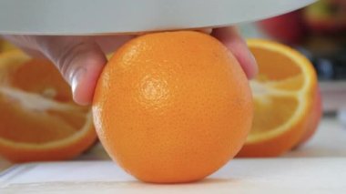 Adam, Sulu Portakal Meyvesini Mutfakta Bıçakla İkiye Kesiyor. Lezzetli bir vejetaryen atıştırması, ferahlatıcı bir vegan kahvaltısı..