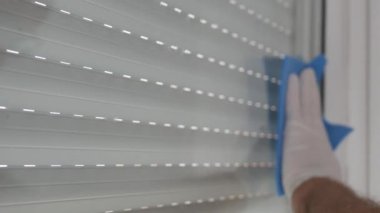 Eldivenle korunan, cam yüzeyini temizleyen, dezenfektan ve temiz mendil kullanan eller..