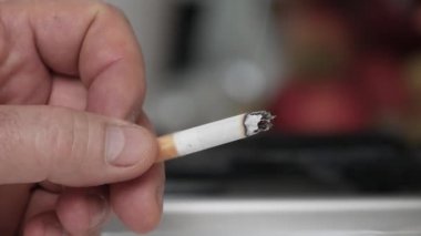Kül tablasında sigara içmek ve söndürmek. Yakın plan, sigara içen bir adamla çekim..