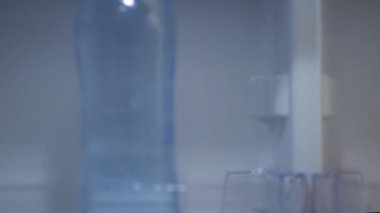 Susamış Kişi Buzdolabının kapısını açar ve Taze ve Soğuk Doğal Suyla bir şişe alır. Gıda Krizi, Boş Buzdolabı Konsepti.