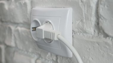 Ofisteki bir prizden elektrik kablosu çıkarıyorum. Elektrik 'ten bir aygıtın fişini çekiyorum. Enerji Krizi, Elektrik Ekonomisi.