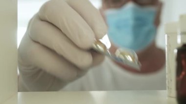 Tıbbi Kişi Maske Giyiyor ve Koruyucu Eldiven Giyiyor İlaç Dolabına Tıbbi İlaçlar Koyuyor.