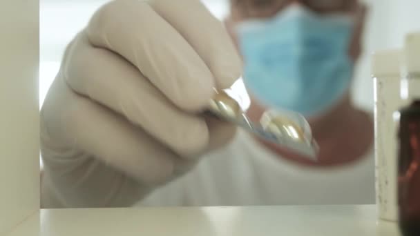 Medizinische Person Mit Chirurgenmaske Und Schutzhandschuhen Legt Medizinische Pillen Ins — Stockvideo
