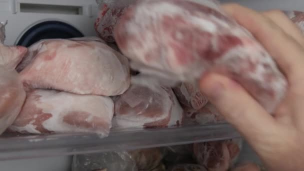 Homme prenant de la viande congelée du congélateur. Réserves de viande congelée, réparties en rations sur les étagères du congélateur. — Video