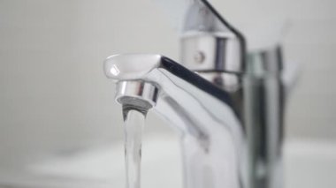 Yetişkin Eldivenleri Giyen Koruyucu Ev Eldiveni Lavabo Musluğu 'nu Banyodan Kapatıyor.