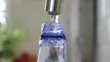 Plastik şişeyi taze suyla dolduruyorum. Bir alıcıda su rezervi yapmak. Su Ekonomisi kavramı.