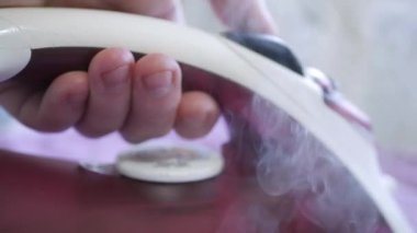 Temizlikçi, modern ütüyle temiz giysiler ütülüyor, Demir Sıcaklığını ayarlıyor ve Buhar Düğmesine basıyor..