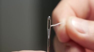 Terzi Eli İğne Deliği 'ne dikiş ipliği sokuyor. İğneyi İplikle Hazırlayan Adam, Ev Yapımı Dikiş Etkinliğine Hazırlanıyor.