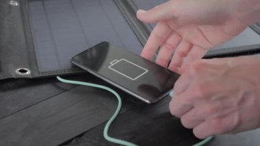 Charging a smartphone with a portable solar panel. Green energy