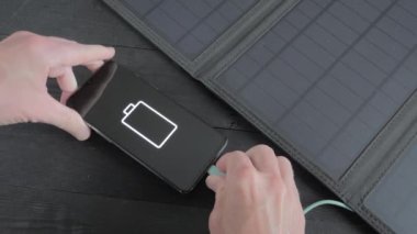 Charging a smartphone with a portable solar panel. Green energy
