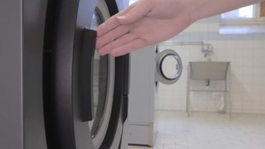 Man opens the door on the washing machine and gets the laundry