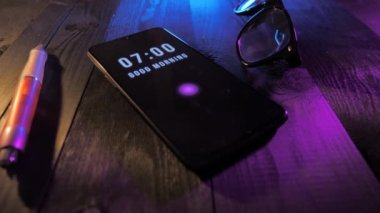Good morning alarm start at 7 am on the smartphone, hand swipes over and turn off alarm. Close up of clock alarm.