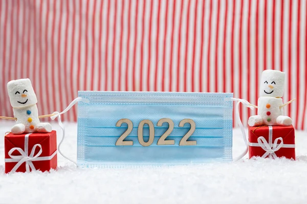 Yeni yıl ve mutlu noeller 2022. Koruyucu maske takan bir çift kardan adam. Yeni Yıl teması.