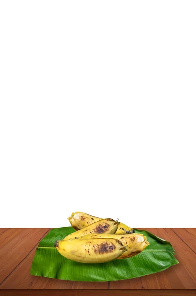 テーブルの上に熟した黄色のバナナと緑のバナナの葉 — ストック写真