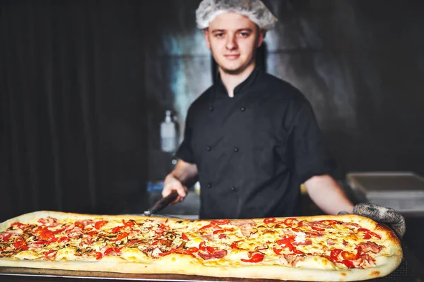 Cuoco Panettiere Cuoco Uniforme Nera Mettendo Pizza Forno Con Pala — Foto Stock