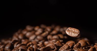 Karanlık bir arka planda uçuşta kahve çekirdekleri