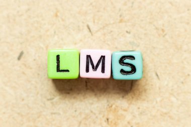 Ahşap zemin üzerinde kelime LMS (Öğrenme yönetim sisteminin kısaltması) renk alfabesi harf bloğu