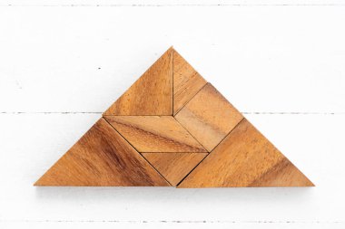 Tahta arka planda üçgen şeklinde ahşap tangram yapbozu