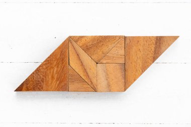 Beyaz ahşap zemin üzerinde paralel kenar şeklinde ahşap tangram yapbozu