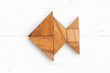 Ahşap arka planda balık şeklinde ahşap tangram yapbozu