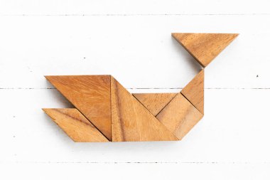 Beyaz ahşap arka planda balina, balık ya da köpekbalığı şeklinde ahşap tangram yapbozu