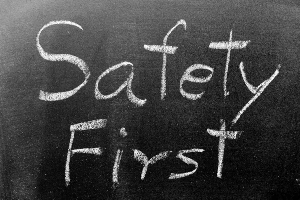 White color chalk hand writing in word safety first on black board background