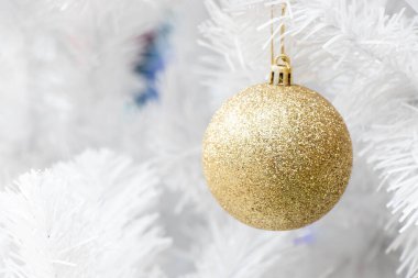 Noel ağacı arkaplanının beyaz dalında altın renkli top (Noel ve Yeni Yıl Festivali Dekorasyonu)