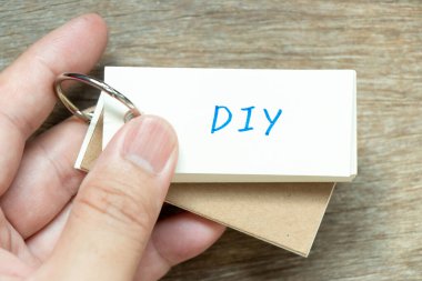 Man flash kartı DIY (kendin yap kısaltması) sözcüğüyle ahşap arka planda tut