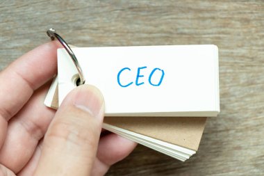 Adam ahşap arka planda el yazısı CEO 'su (Genel Müdür Kısaltması) ile flaş kartı tutun