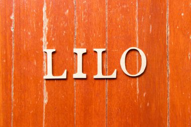 Alphabet letter in word LILO (abbreviation of last in last out) on old red color wood plate background