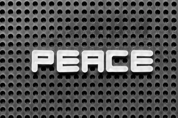 黒のペグボードの背景に単語の平和の白いアルファベット — ストック写真