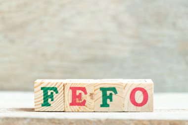 Tahta zemin üzerinde FEFO harfleriyle alfabe harfi bloğu (ilk kez ilk kez geçerlidir)