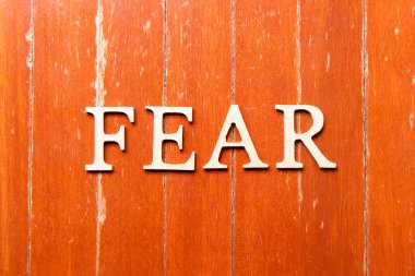 Alfabe harfleri eski kırmızı ahşap arka planda kelime korkusudur.