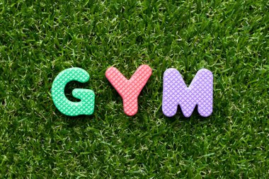 Yeşil çimen arka planında spor salonunda oyuncak köpük harfi.